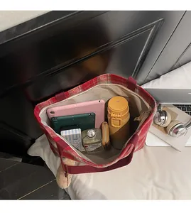 Macro view showing large capacity of the red checkered tote bag with daily essentials