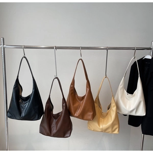 Five assorted colors of large PU leather tote bags displayed on a minimalist metal rack
