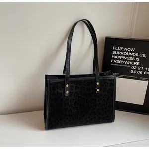 Detailed close-up of leopard print texture and gold rivet studs on black tote bag