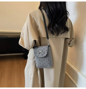 Close-up of grey mini shoulder bag with heart embroidery and silver metal bow detail