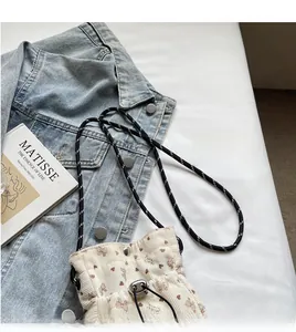 Detail of light beige corduroy crossbody bag with floral bow print and adjustable rope strap