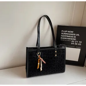 Detail of leopard print tote bag with metal studs and ethnic style tassel charm