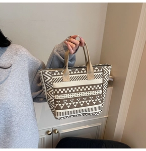 Detailed side view of canvas tote bag with geometric brown patterns on cream fabric