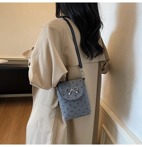 Gray felt crossbody bag with heart pattern and silver bow detail on model in trench coat