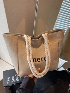 Large khaki straw tote bag with rope handles and merci print for summer beach or commute