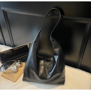 Macro detail of black crinkle-textured tote bag with laptop and office accessories