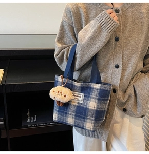 Detail of blue plaid canvas tote bag with soft mushroom charm and logo label