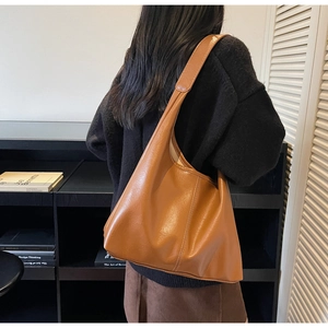 Close-up of a brown PU leather tote bag with wide strap and detailed contrast stitching