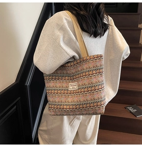 Rear view of model carrying ethnic geometric woven tote bag on a wooden staircase