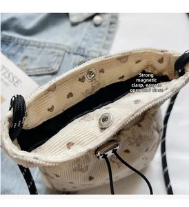 Detail view of the strong magnetic buckle and beige corduroy fabric texture on the crossbody bag