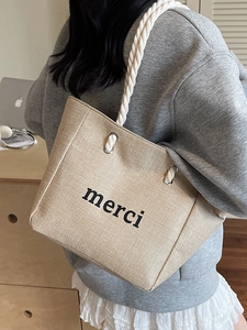 Minimalist beige linen tote bag with merci print and cotton rope handle in daily use