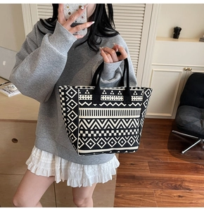 Detail of canvas tote bag featuring black and white geometric tribal patterns with soft handles