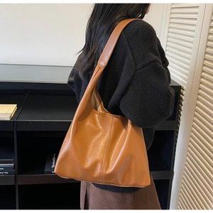 Detailed side view of caramel PU leather tote bag with vertical stitching on hobo style