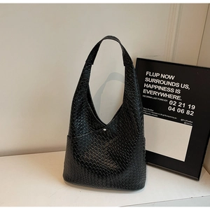 Close-up of black woven leather texture and silver magnetic clasp on tote bag