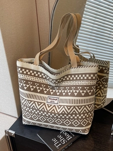 Large canvas tote bag with geometric patterns and brown trim in a cozy indoor setting