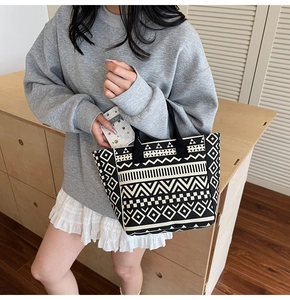 Detail of a black and white geometric tribal pattern on a canvas tote bag worn by a model