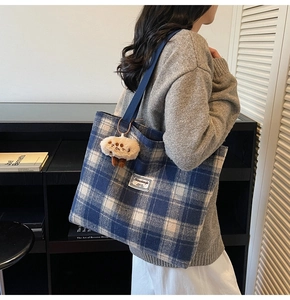 Detail of blue plaid canvas tote bag with a cute plush mushroom charm on the strap
