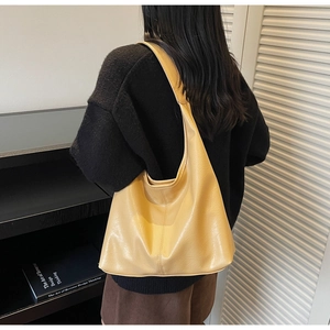 Macro shot of textured yellow leather tote showing the wide strap and draped silhouette