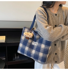 Detail of blue plaid canvas tote bag with mushroom charm and woven straps