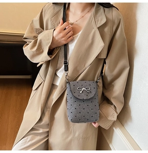 Detail of grey heart pattern crossbody bag with silver bow buckle and black strap