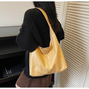 Close-up of mustard yellow leather tote bag with wide shoulder strap on a model