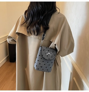 Detail view of mini grey polka dot crossbody bag with silver bow accent and leather strap