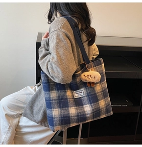 Detail of blue and white checkered tote bag with plush cloud charm and woven strap