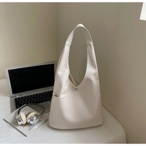 Detail of minimalist beige tote bag featuring faux crocodile texture and magnetic closure