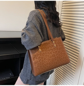 Detail of leopard print tote bag with suede texture and metal rivet strap accents