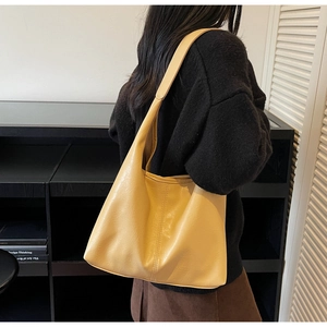 Detail view of large yellow faux leather tote bag showing texture and wide shoulder strap