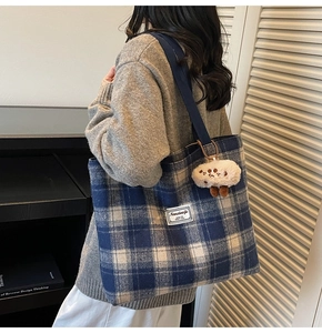 Detail of blue plaid tote bag with plush lamb charm and durable canvas shoulder strap