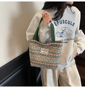 Detail of colorful geometric woven tote bag with green handles and brand label
