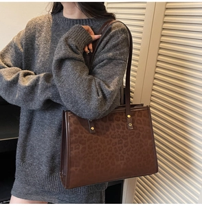 Detailed view of leopard print tote bag with brown leather handles and golden metal rivets