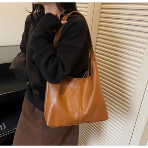 Detail of caramel tote bag with premium leather texture and stitching shown on shoulder
