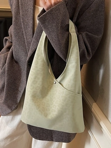 Light green leopard jacquard tote bag shown on a model in a minimalist indoor setting