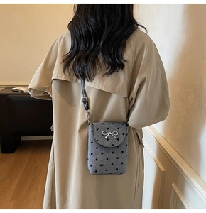 Detail of grey felt polka dot crossbody bag with silver bow on khaki trench coat