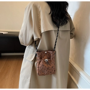 Detail of brown corduroy crossbody bag with black bow patterns and braided rope strap