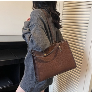 Detail of leopard print tote bag featuring dual shoulder straps and gold rivet accents