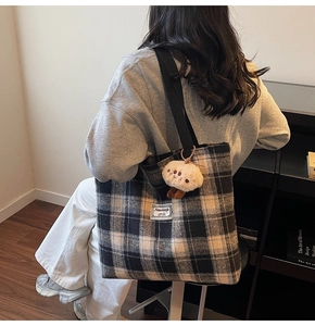 Detail view of large checkered tote bag with brand label and plush mushroom pendant