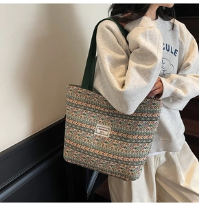 Detail of colorful geometric woven tote bag featuring a green strap and a logo patch