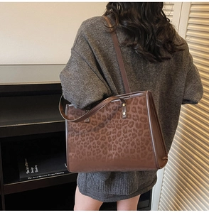 Detail of leopard print tote bag with brown leather handles and textured fabric finish