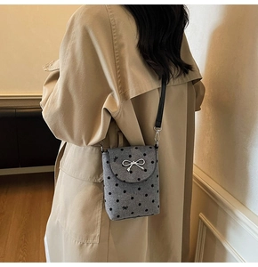 Macro shot of grey wool felt crossbody bag featuring black polka dots and silver bow detail