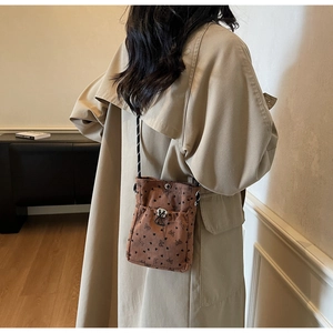Detail of brown corduroy crossbody phone bag with butterfly patterns on a trench coat