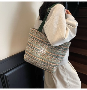 Detail of bohemian woven tote bag with geometric patterns and green shoulder strap