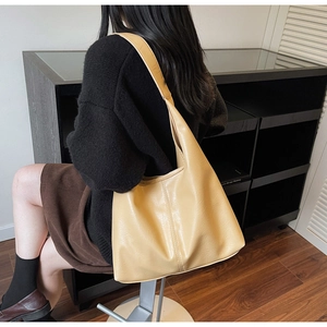 Model showing large yellow leather hobo tote bag with vertical stitching and sleek strap