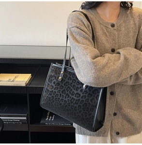 Detail of large leopard print tote bag with plush texture and long black leather straps