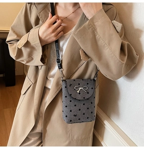Detail view of mini grey wool crossbody bag with black polka dots and silver metal bow