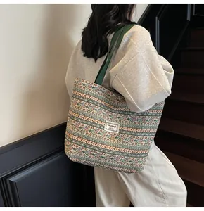 Ethnic style woven tote bag with geometric patterns shown on shoulder of a model
