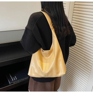 Detailed side view of large yellow PU leather hobo bag worn by a model for size comparison