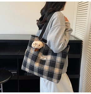 Detail of checkered tote bag with plush charm shown on a model in a casual setting